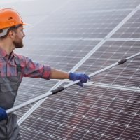 Male worker cleaning solar panels